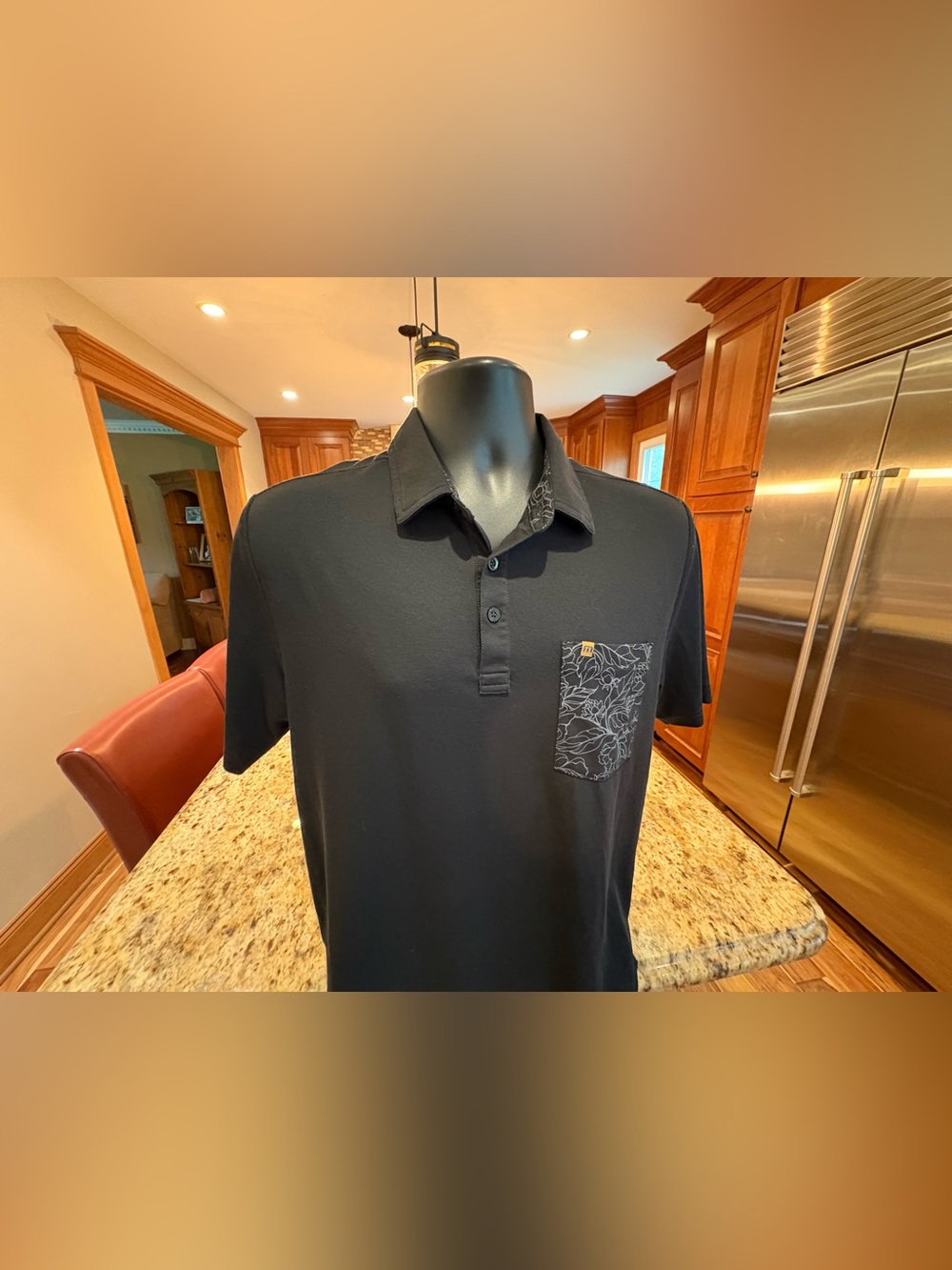 Travis Mathew men’s golf polo. Sharp black with Patterned Chest Pocket & logos.
